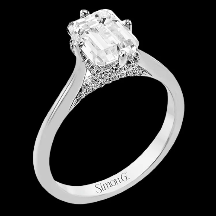 Women’s oval engagement rings-This elegant white gold engagement ring takes an Emerald center and is adorned with a delicate under halo, and a line of diamonds on the side profile 0.13 ctw